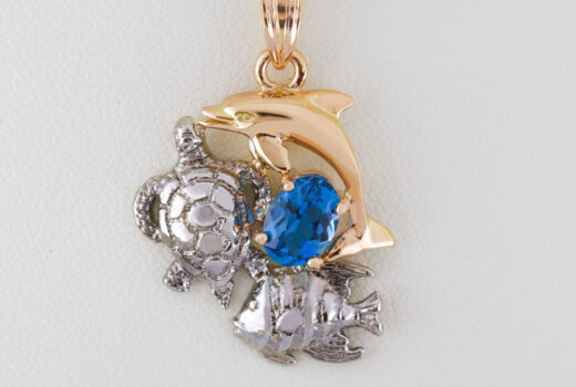 Dolphin, Turtle and Angelfish, the three creatures surrounds a blue topaz gemstone.